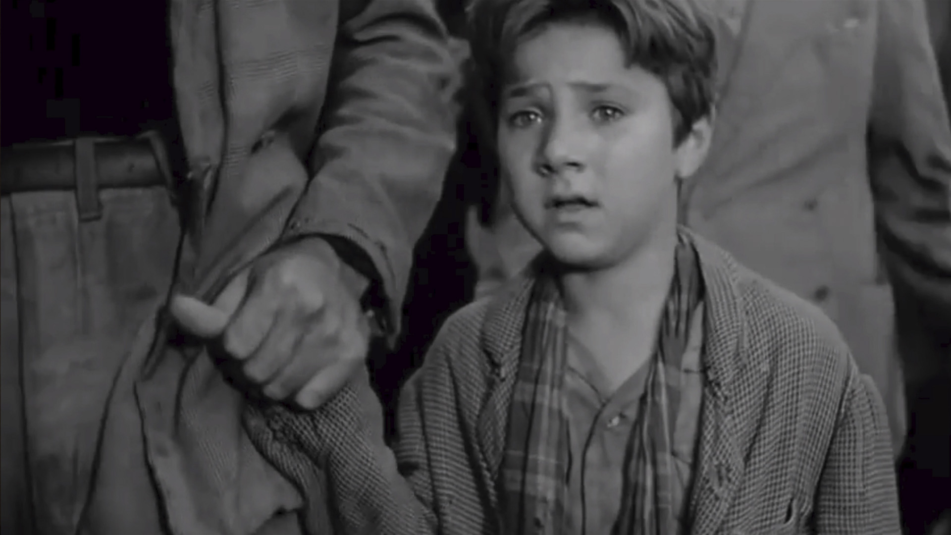 The boy from the film still looks with tears in his eyes at what his father did, holding the hand of someone nearby